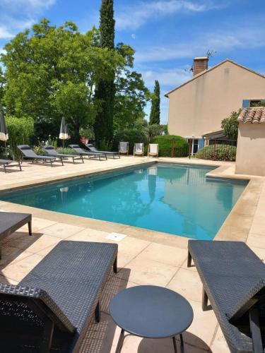 - une piscine avec des tables et des chaises à côté d'un bâtiment dans l'établissement La Garance, à Bédoin