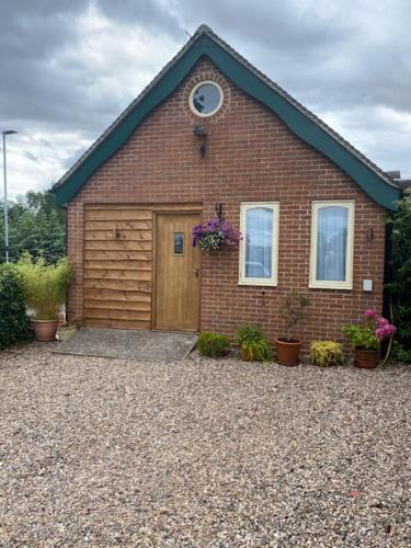 a red brick house with a wooden door at Newton House Apartment, Newton Burgoland in Heather