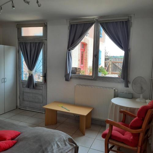 a living room with a table and two windows at Gîte à la ferme avec piscine in Bernadets-Debat
