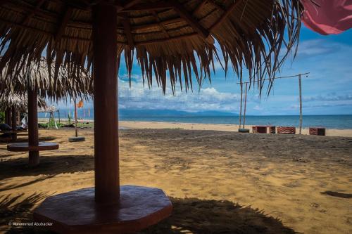 a straw umbrella on a beach with the ocean at Camaya-an Paradise Beach Resort in Malabugas