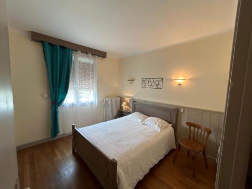 a bedroom with a bed and a chair and a window at le Jardin d'Odette in Yèvres-le-Petit