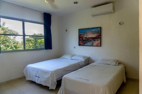 two beds in a room with two windows at Suites 2 habitaciones triple in Progreso