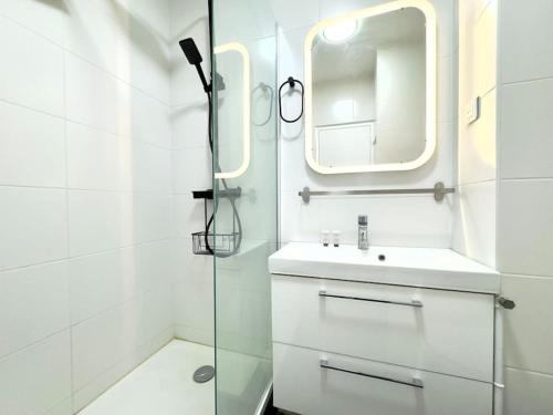 une salle de bain blanche avec un lavabo et un miroir dans l'établissement Appartement Cosy 2P- Trocadero La Muette, à Paris
