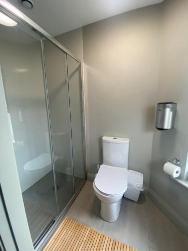 a bathroom with a toilet and a glass shower at Heyday Hostel Ballina in Ballina