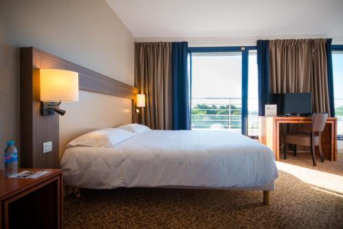 a hotel room with a bed and a desk with a computer at Brit Hotel Saint Malo – Le Transat in Saint Malo