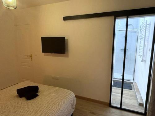 - une chambre avec un lit et une télévision murale dans l'établissement Le Chic & Relax, proche Centrex, à Noisy-le-Grand