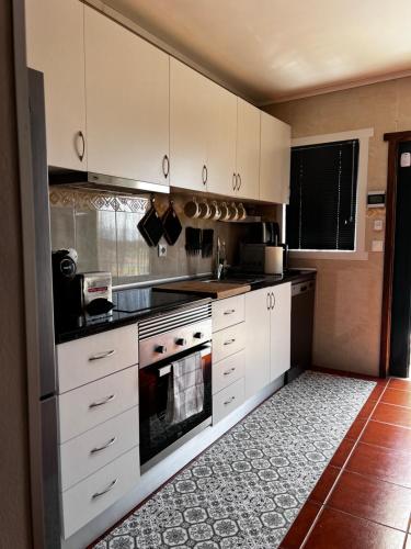 eine Küche mit weißen Schränken und einem Herd mit Backofen in der Unterkunft Casa Da Serra in Oliveira de Frades