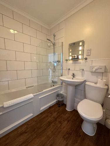 a bathroom with a tub and a toilet and a sink at The White Hart Hotel in Welwyn