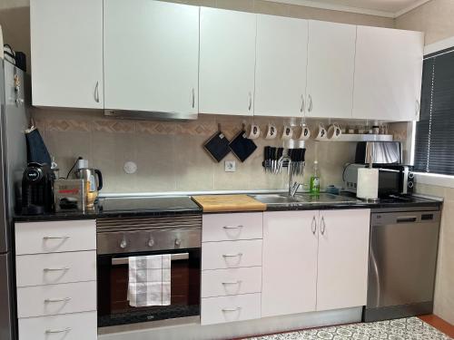 eine Küche mit weißen Schränken und Geräten aus Edelstahl in der Unterkunft Casa Da Serra in Oliveira de Frades