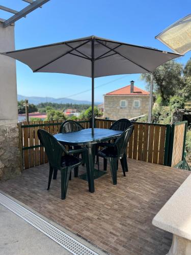 a table and chairs with an umbrella on a deck at Casa Da Serra in Oliveira de Frades