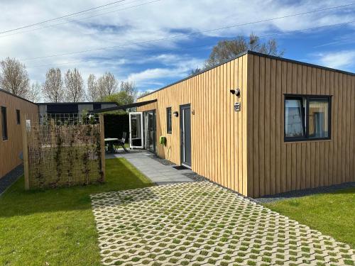a wooden house with a gate and a patio at Vakantie Chalet met hottub in Ibiza stijl te Zeeland in Heinkensand
