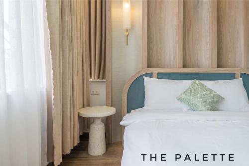 a bedroom with a bed with a table and a bed sidx sidx sidx at The Palette Dalat in Da Lat