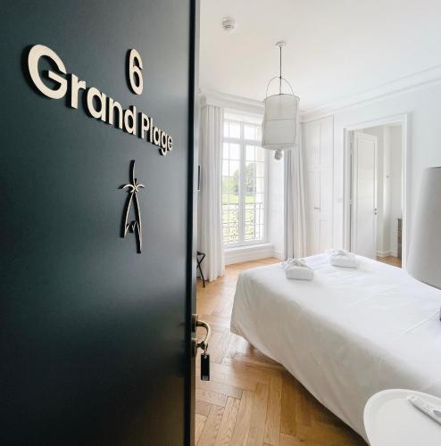 a bedroom with a bed and a door with the words grandplaces at Les Garennes - Hôtel Spa Bénodet in Bénodet