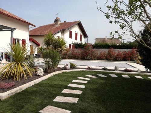 un jardin avec une pelouse et une maison dans l'établissement Jolie Maisonnette de 37 m2 meublée, à Saint-Vincent-de-Tyrosse