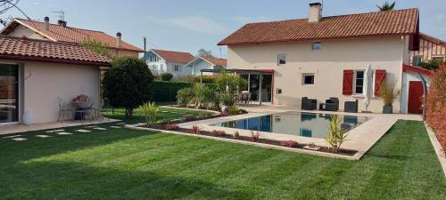 une maison avec une piscine dans une cour dans l'établissement Jolie Maisonnette de 37 m2 meublée, à Saint-Vincent-de-Tyrosse