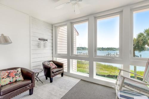 a living room with two chairs and large windows at Mariners Cay 74 in Folly Beach