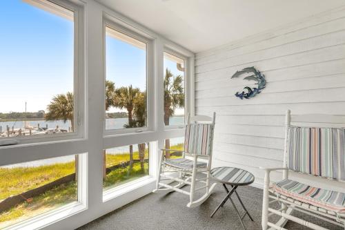 two rocking chairs in a room with windows at Mariners Cay 74 in Folly Beach