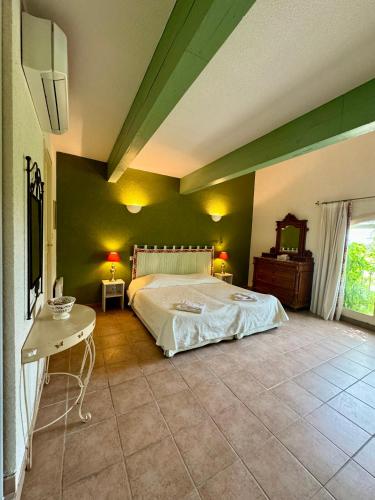 - une chambre avec un grand lit et des murs verts dans l'établissement Mas du Grand Peloux, à Port-Saint-Louis-du-Rhône