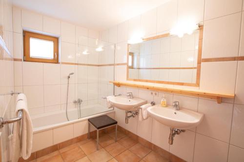 a bathroom with two sinks and a tub and a mirror at Almhäuser Filzsteinalpe Almhaus 205 in Krimml