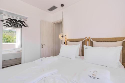 a bedroom with a large white bed with white pillows at Metsikas Residence in Limenas