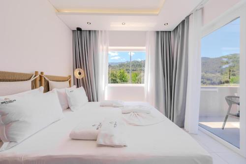 a bedroom with two white beds and a window at Metsikas Residence in Limenas