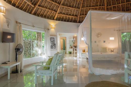 una stanza con un letto, un tavolo e delle sedie di Watamu Beach Cottages a Watamu