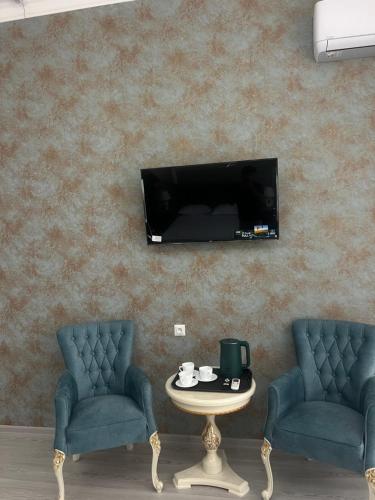 twee stoelen en een tafel met een tv aan de muur bij Best Ali Samira new hotel in Bukhara