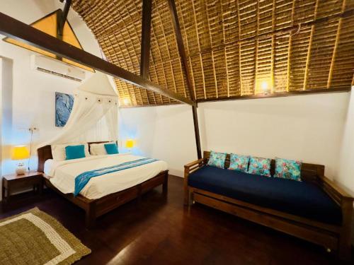 a bedroom with a bed and a couch in a room at Tiga Kelapa Villa by Smart Digital in Legian