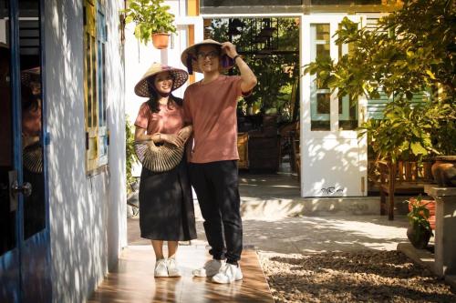 a man and woman wearing hats standing outside a building at Trại Hoa Vàng Homestay at Phú Yên in Ðông Tác (1)