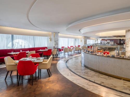 a restaurant with red chairs and tables and a bar at The Hotel Galleria Jeddah, Curio Collection by Hilton in Jeddah