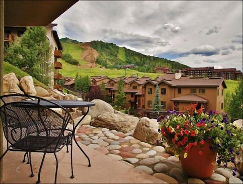 a patio with a table and chairs and flowers at Pool, Hot Tub, Sauna, Amazing Ski Area Views, Partially Covered Patio in Steamboat Springs