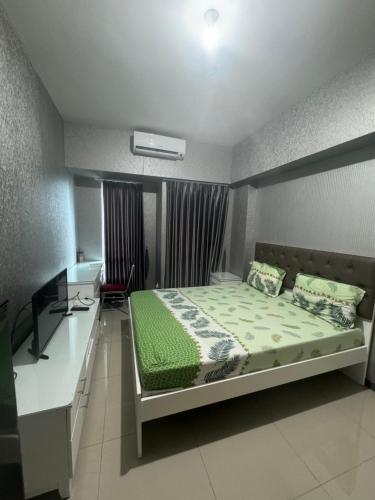 a bedroom with a bed and a desk in it at Apartment Anderson Benson Orchard Tanglin Tower di atas Pakuwon Mall Surabaya Barat in Lontar