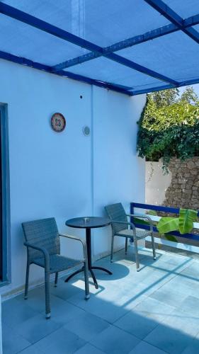 a patio with three chairs and a table with a blue umbrella at Iris Studios in Archangelos