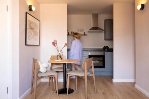 a woman in a kitchen with a table and chairs at Bob W London St Paul's in London
