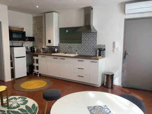 une cuisine avec des armoires blanches et une table dans l'établissement Calme et idéalement placé, à Avignon