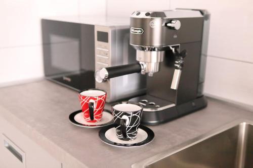 a coffee machine with two cups on a counter at Modern apt in Dubec, ideal for couple in Sesvete