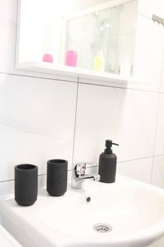 a bathroom sink with a faucet and two cups on it at Modern apt in Dubec, ideal for couple in Sesvete