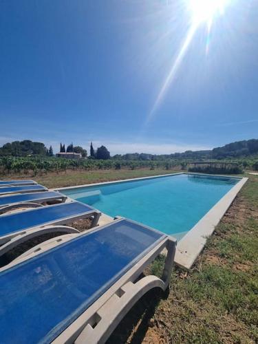 une rangée de piscines bleues dans un champ au soleil dans l'établissement Une Nuit au Cœur d'un Vignoble Provençal Piscine, à Cotignac