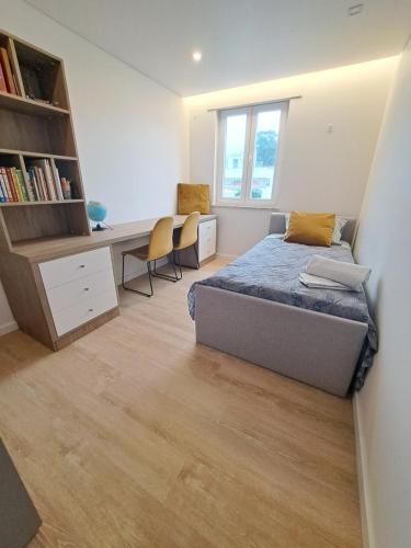 a bedroom with a bed and a desk with chairs at Casa dos Paralelos in Moledo