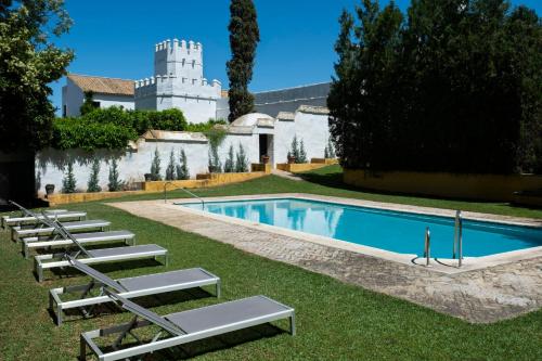 トレ・デ・ラ・レイナにあるCortijo Torre De La Reinaの建物の隣にプール(ラウンジチェア付)があります。