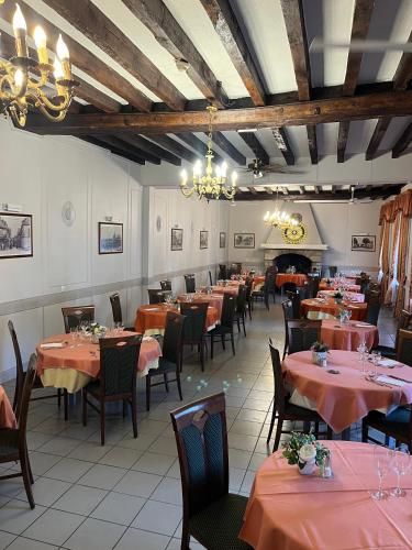 - une salle à manger avec des tables, des chaises et du linge de maison orange dans l'établissement Le Relais De La Poste, à Pithiviers