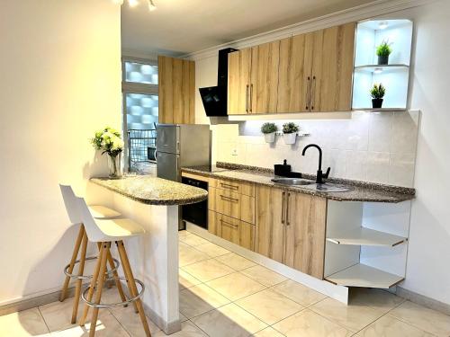 a kitchen with wooden cabinets and a sink and a counter at Tropicalife in Playa del Ingles