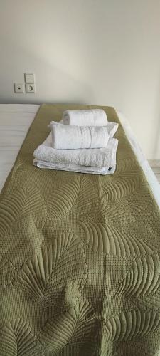 a bed with three towels on top of it at Coralli Loft in Nea Anchialos
