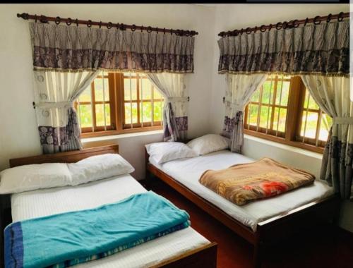 two twin beds in a room with windows at Acme Divine View in Nuwara Eliya
