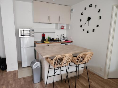 une cuisine avec une table, deux chaises et une horloge dans l'établissement 2 Pièces calme proche Paris, à Suresnes