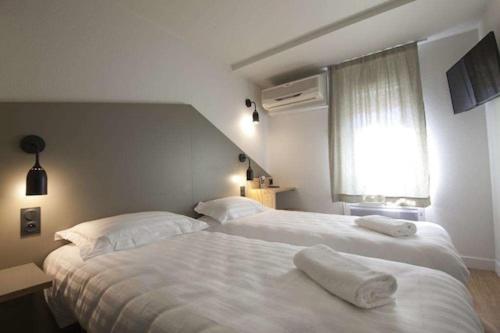 a bedroom with two beds with towels on them at Brit Hotel Essentiel Arverne - Clermont-Ferrand Sud in Aubière