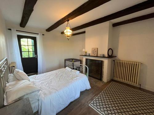 a bedroom with a white bed and a fireplace at La maison Novalia in La Rouquette