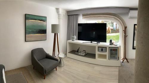 a living room with a tv and a chair at Hotel Boutique de Cantera Y Plata in Taxco de Alarcón