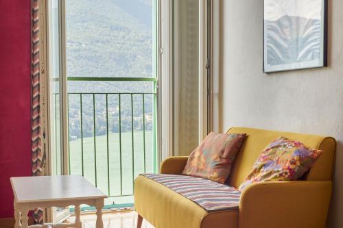 a living room with a couch and a large window at Timeless Charm - A Window to Lake Como in Blevio