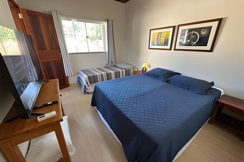 a bedroom with a blue bed and a television at Linda Casa C/ Vista pro Mar na Praia Grande em Paraty in Paraty